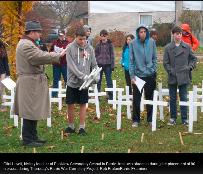 Facing History educator Clint Lovell and his students laying down crosses to commemorate fallen soldiers from Barrie, ON during WWI.  Photograph originally published in the Barrie Examiner.  Credit: Bob Bruton