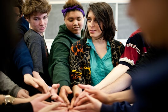 students bring their hands together in solidarity with their teacher